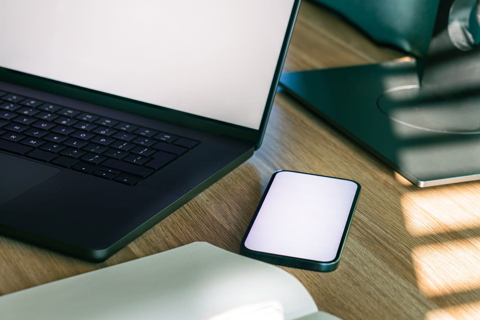 Laptop and smartphone on a desk showing a synced workspace