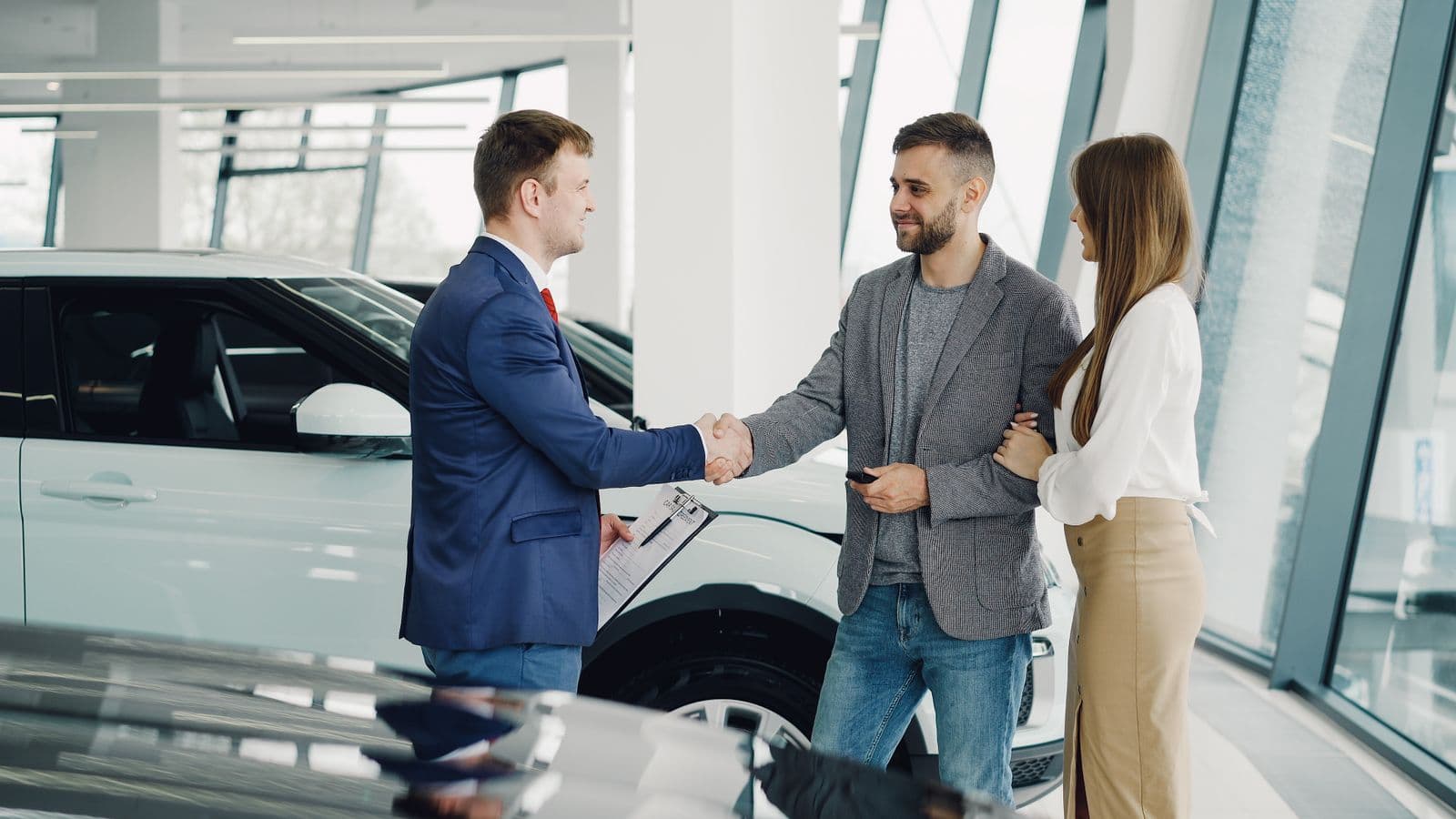 Car salesman shaking hands with a customer in a showroom