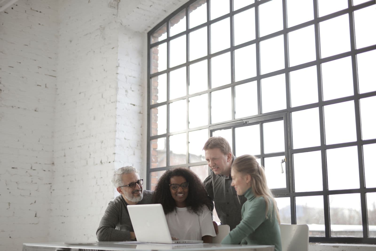 Business team collaborating around a laptop in a bright office