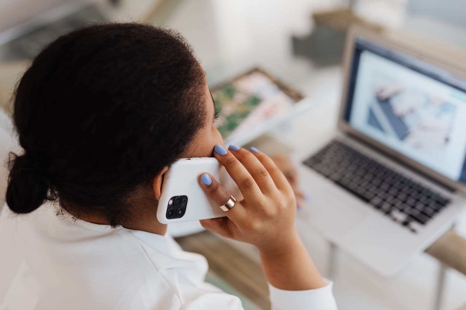 Person using a phone and laptop together at a desk
