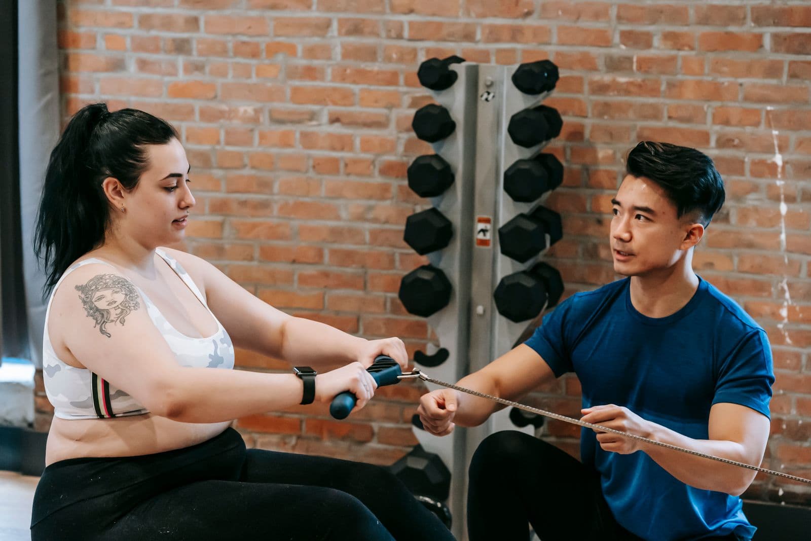 Personal trainer helping a member with weights in a gym