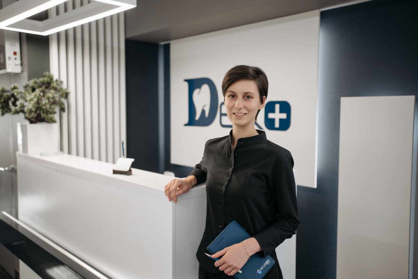 Clinic receptionist smiling at the front desk