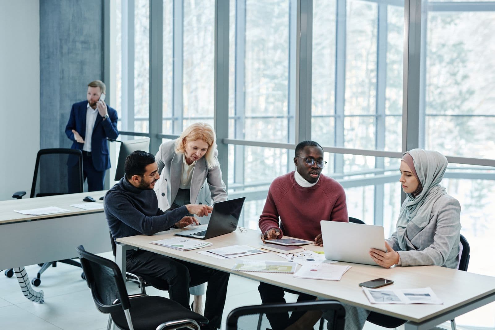 Diverse business team collaborating in an office on laptops