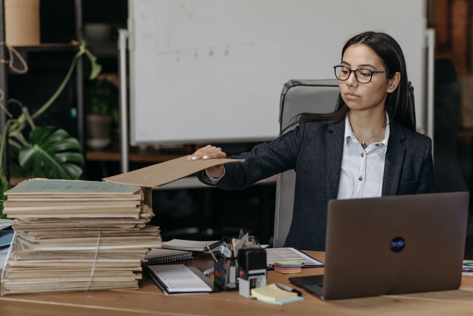 Business person organising files at a laptop in an office