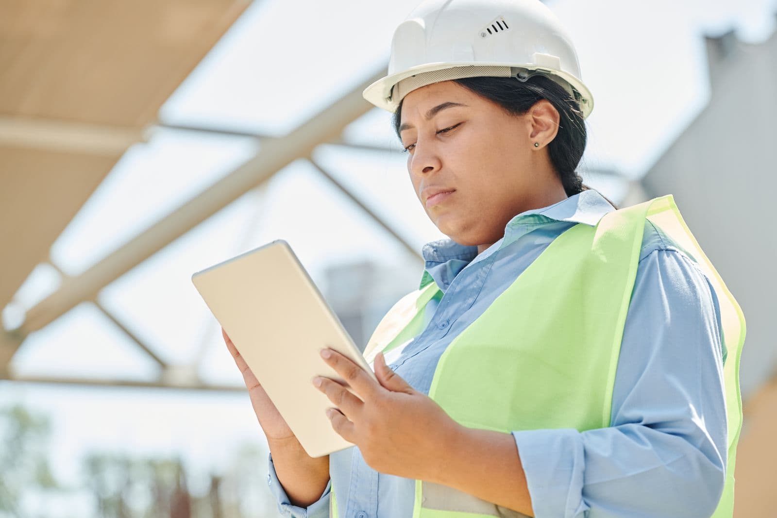 Construction engineer in a hard hat using a tablet on site